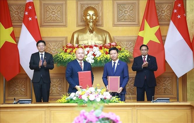 越南政府总理范明政与新加坡总理黄循财共同见证越南友好协会与新加坡国际基金会合作备忘录的签署。图自越通社