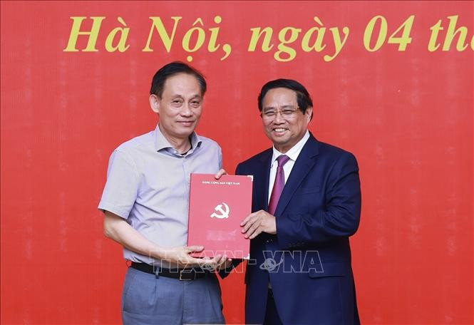 范明政总理向黎怀忠同志颁发中央政治局的决定。图自越通社