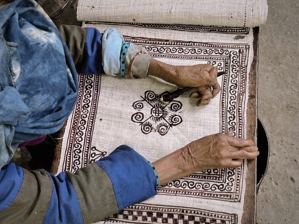 在粗布底料上以蜂蜡描绘纹样。图自 越通社