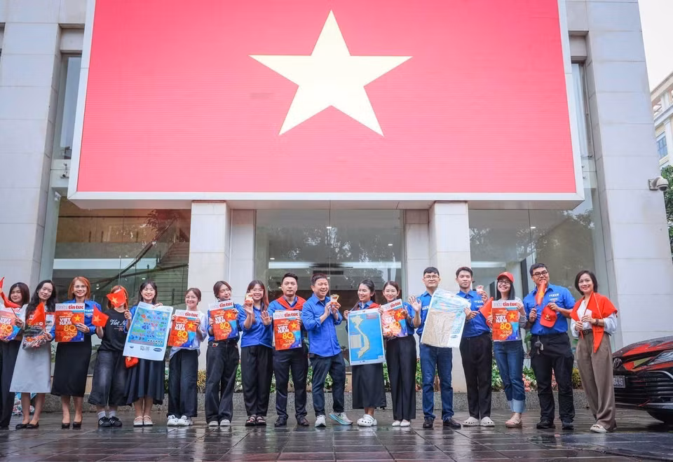 越南通讯社青年团在总部与大型国旗合影留念。图自 越通社