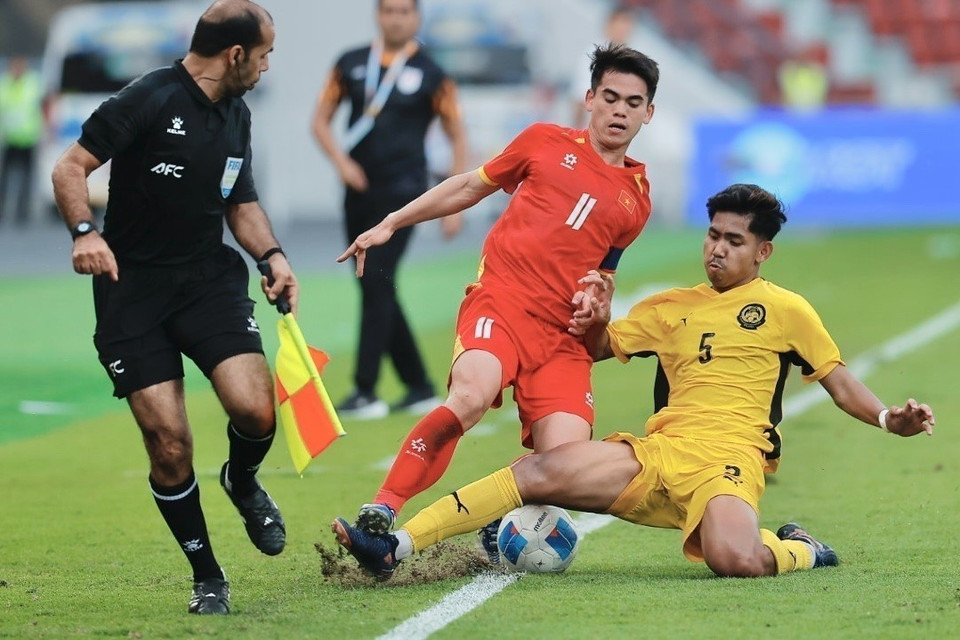 马来西亚U22队球员拼尽全力阻挡屈文慷的带球突破。图自 越通社