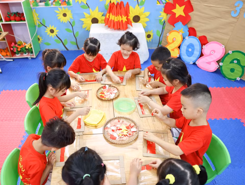 幼儿们认真细致地剪贴制作心中热爱的鲜艳祖国国旗。图自 越通社