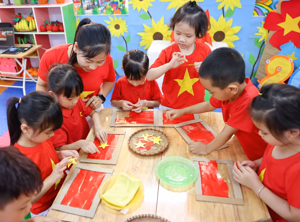 幼儿们认真细致地剪贴制作心中热爱的鲜艳祖国国旗。图自 越通社