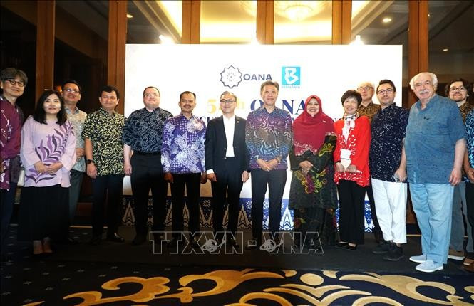 出席亚通组织执行委员会第54次会议的代表们身着马来西亚巴迪克国服，与马来西亚通讯和数字部长法赫米·法兹尔一同合影留念。图自 越通社