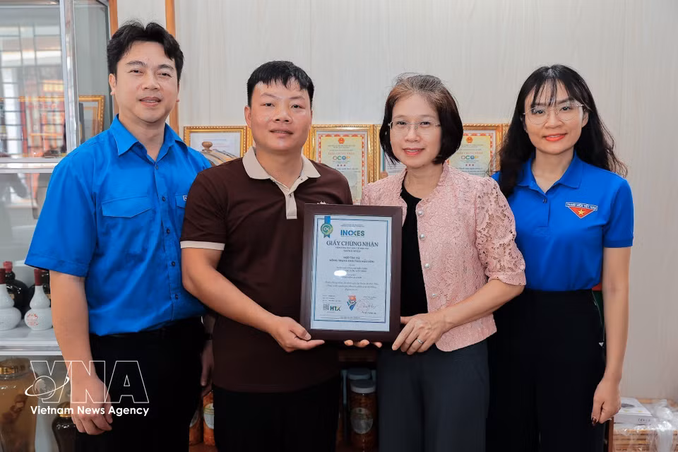 越南合作社联盟副主席阮氏怀玲向母山生态农场合作社颁发“阿穆伊叶酿酒”产品来源追溯认证证书，该产品已在hoptaxa.vn系统完成追溯认证。图自 越通社