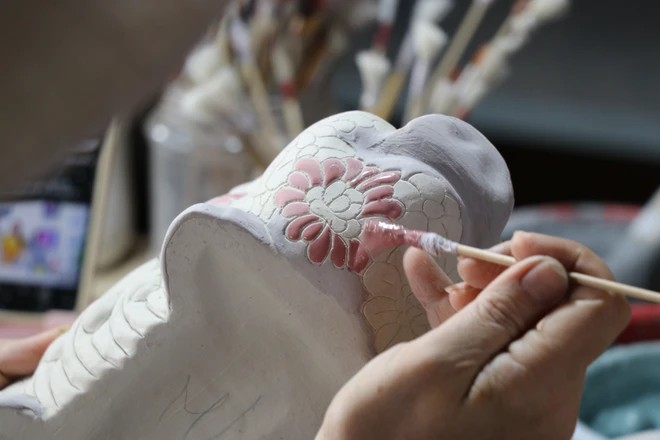 峰山陶瓷作坊的工匠们为陶瓷产品上釉并彩绘装饰。图自越通社