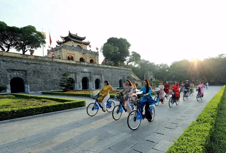 身着传统奥黛的首都女性骑自行车穿过河内的多个遗产景点，参家“2023年首次‘奥黛连接河内旅游与遗产’活动”。图自 越通社