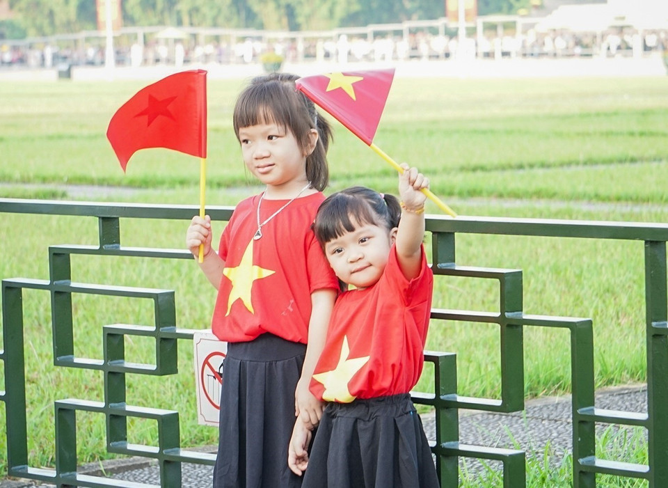 许多父母还带着孩子早早到场，参加在巴亭广场举行的升旗仪式。” 图自 越通社