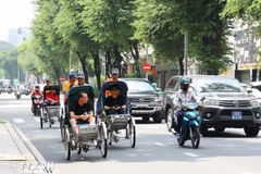 游客乘坐人力三轮车参观胡志明市中心。图自越通社