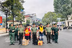 执法力量将19名犯罪嫌疑人押解过老街国际口岸。图自越通社