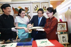 越南政府总理范明政与泰国总理佩通坦参观了解越南东胡画制作工艺。图自越通社