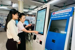 广宁省综合医院医务人员指导民众使用自助挂号机。图自Vietnam+