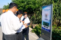 林同省游客在富贵特区主权旗台景点扫描二维码，快速获取旅游信息。图自越通社