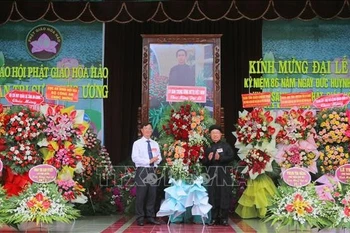 安江省越南祖国阵线委员会副主席裴文赠（左）送花祝贺和好佛教创立86周年。图自越通社