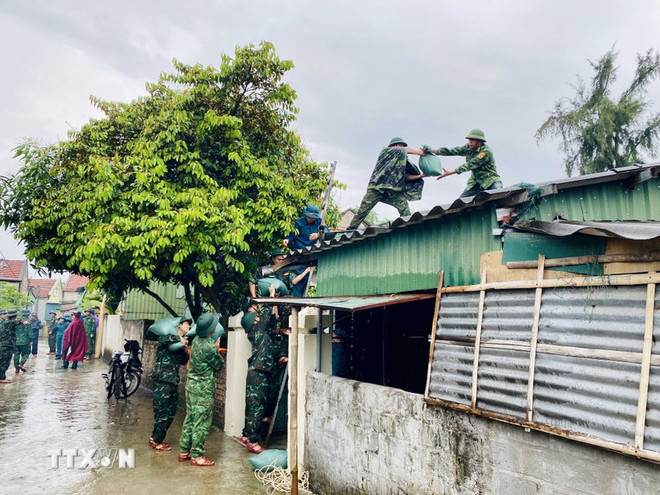士兵们为河静省丹海乡居民加固屋顶。图自越通社 luc-luong-quan-doi-ho-tro-nguoi-dan-ha-tinh-ung-pho-bao-so-3-8162182.jpg