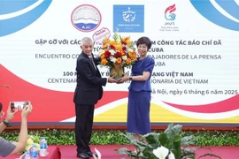 古巴拉丁美洲通讯社驻越代表向越通社社长武越庄赠送鲜花，祝贺越南革命新闻日。图自越通社