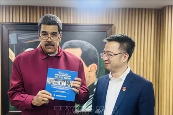马杜罗总统接收由阮祥林赠送的《世界人民对胡志明主席的感情》（西班牙语版）书籍。图自越通社