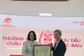 越南国家文书与档案局局长邓青松向俄罗斯驻越大使夫人埃琳娜·贝兹德特科赠送一幅越南国号的木刻版画。图自越通社