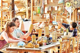 在岘港的一家手工艺品作坊里，游客们用竹子制作自己的纪念品。图自《人民报》