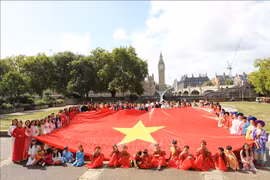 身着越南传统服饰的在英越南人参加在伦敦市中心举行的游行活动。图自越通社