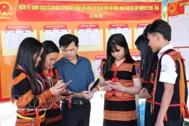 岘港市茶灵乡色当族同胞正在用手机查看有关第十六届国会及各级人民议会代表选举的视频和图表新闻，了解投票流程。图自越通社