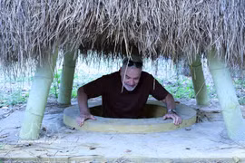 外国游客体验奇英地道当地居民院子里的地道口。图自越通社