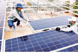 越南工人在胡志明市安装太阳能发电系统。图自《人民报》 