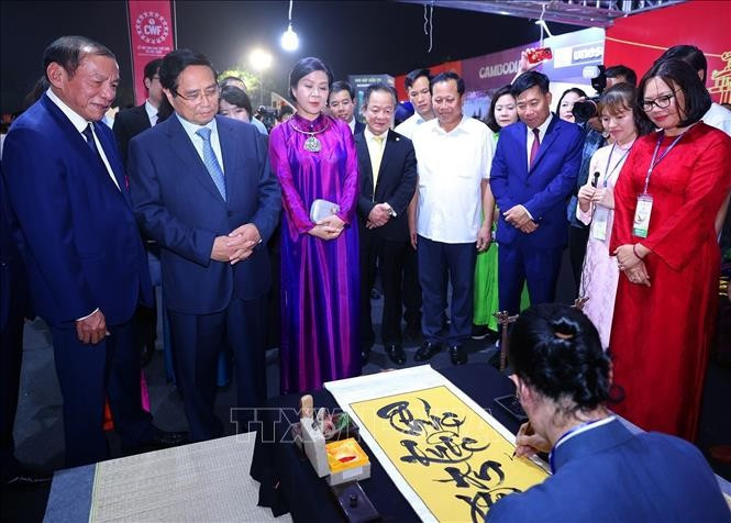 越南政府总理范明政、越共中央总书记苏林夫人吴芳璃和各位代表欣赏书法大师展示才艺。图自越通社