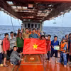 胡志明市海上执法力量向正在海上作业的渔民赠送国旗，并进行打击IUU相关内容宣传。图自越通社
