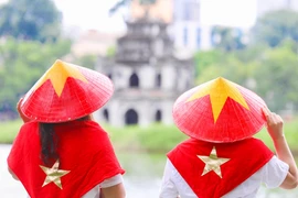 年轻人身穿金星红旗斗笠与配件，以此彰显爱国情怀。图自越通社