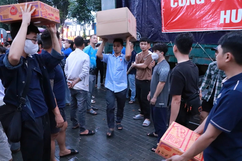 志愿者们正忙碌地将80吨物资和生活必需品装上救援车辆,送往灾区。图自越通社