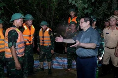 范明政总理慰问激励正在加固堤防、防止洪水漫溢,确保右桥堤段安全的的抢险力量。图自越通社