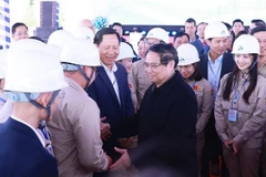 政府总理范明政在工程开工仪式上与工人们亲切握手。图自越通社