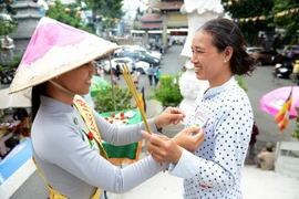 衣上带着白色玫瑰花的胡志明市范氏情女士（右）