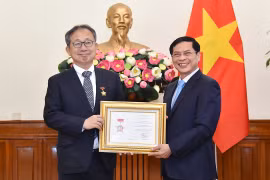裴青山向山田贵雄大使授予“致力于越南外交事业”纪念章。图自越通社