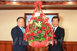 阮伯雄大使向老挝人民革命党中央对外部副部长赛逢·西茶伦移交越共中央总书记阮富仲和越南驻老大使馆的花篮。（图片来源：越通社）