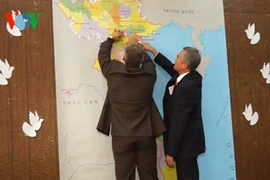 越南驻乌克兰大使阮明智与乌克兰—越南友好协会主席亚历山大将纸鸽子贴在越南地图上。