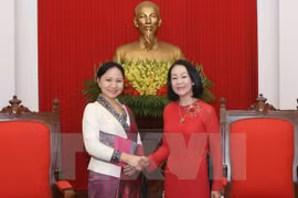 越共中央民运部部长张氏梅（右）与老挝妇女联合会主席因塔万（左）亲切握手