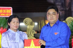 胡志明市团市委书记、胡志明市越南青年联合会主席吴明海向烈士家属移交烈士遗像。图自越通社