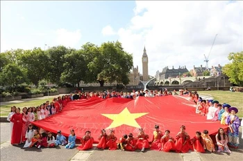 身着越南传统服饰的在英越南人参加在伦敦市中心举行的游行活动。图自越通社