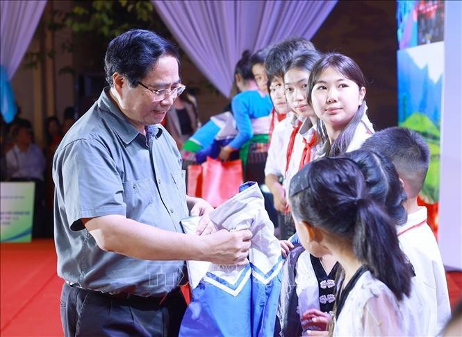 范明政总理向学生们赠送礼物。图自越通社