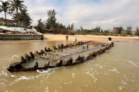 越南岘港市会安西坊新城海滩上出现一艘有数百年历史的木船出现在海滩上。图自《岘港报》