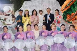 越南外交部副部长、海外越南人国家委员会主任黎氏秋姮、越南驻新加坡大使陈福英与表演者合影。图自越通社