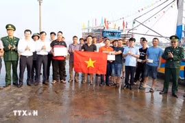 广治省人民委员会副主席黎文宝（上排右四）向渔民赠送礼物，并提醒渔民严格遵守打击IUU捕捞规定。图自越通社