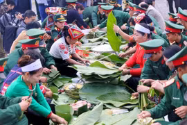 少数民族与战士们在越南各民族文化旅游村一起包粽子。图自越通社