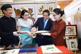 越南政府总理范明政与泰国总理佩通坦参观了解越南东胡画制作工艺。图自越通社