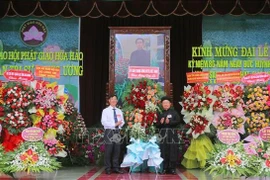 安江省越南祖国阵线委员会副主席裴文赠(左)送花祝贺和好佛教创立86周年。图自越通社
