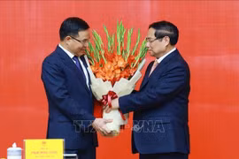 范明政总理向黎孟雄同志送花祝贺。图自越通社