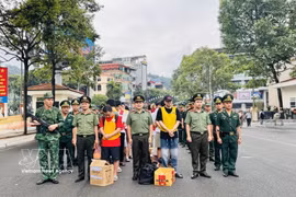 执法力量将19名犯罪嫌疑人押解过老街国际口岸。图自越通社
