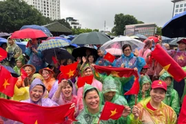 在大雨中，首都河内的市民无惧恶劣天气，耐心守候，只为即将登场的武装力量方阵加油助威。图自越通社。
